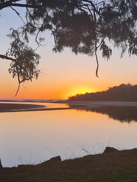 A tropical sunrise over a still river mouth to the sea.