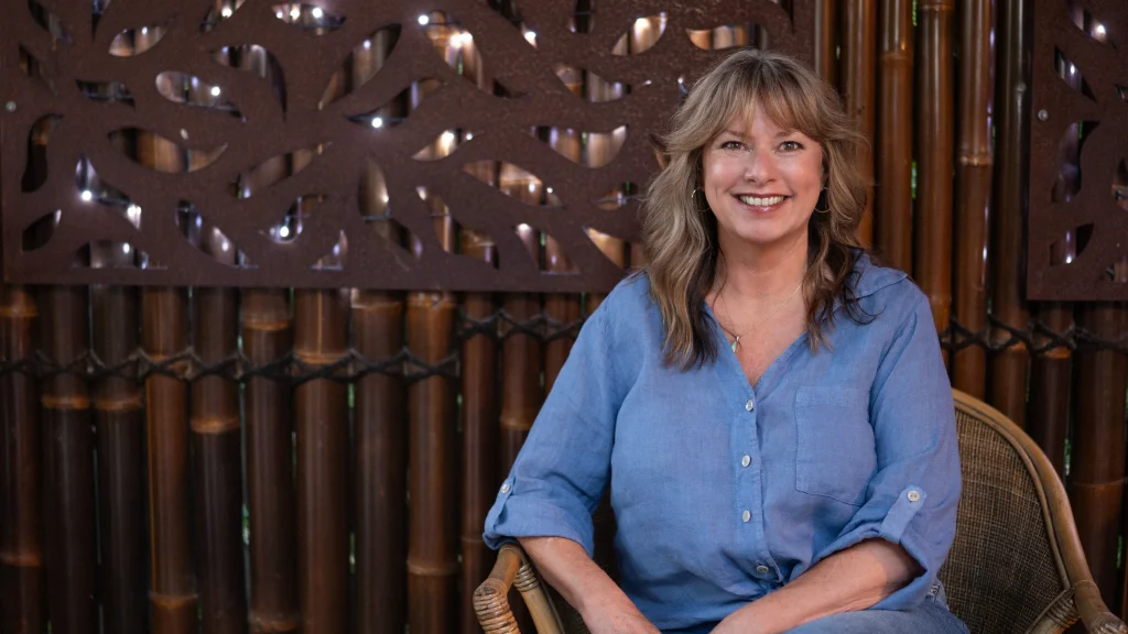 Kimberley sitting outside with what looks like a Balinese wood background.
